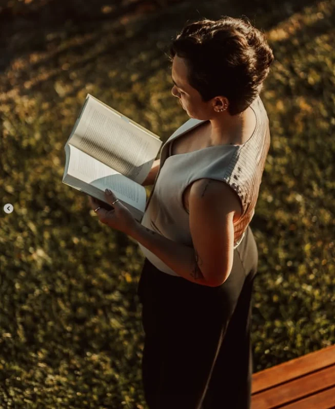 Solange Kappes lendo um livro ao ar livre, no fim de tarde